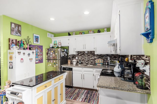 kitchen with appliances with stainless steel finishes, backsplash, dark stone counters, sink, and white cabinets