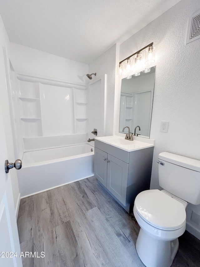 full bathroom with washtub / shower combination, wood-type flooring, vanity, and toilet