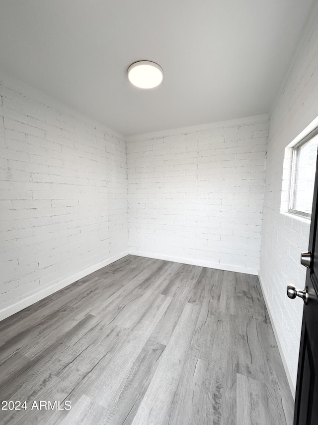 empty room featuring light wood-type flooring and brick wall