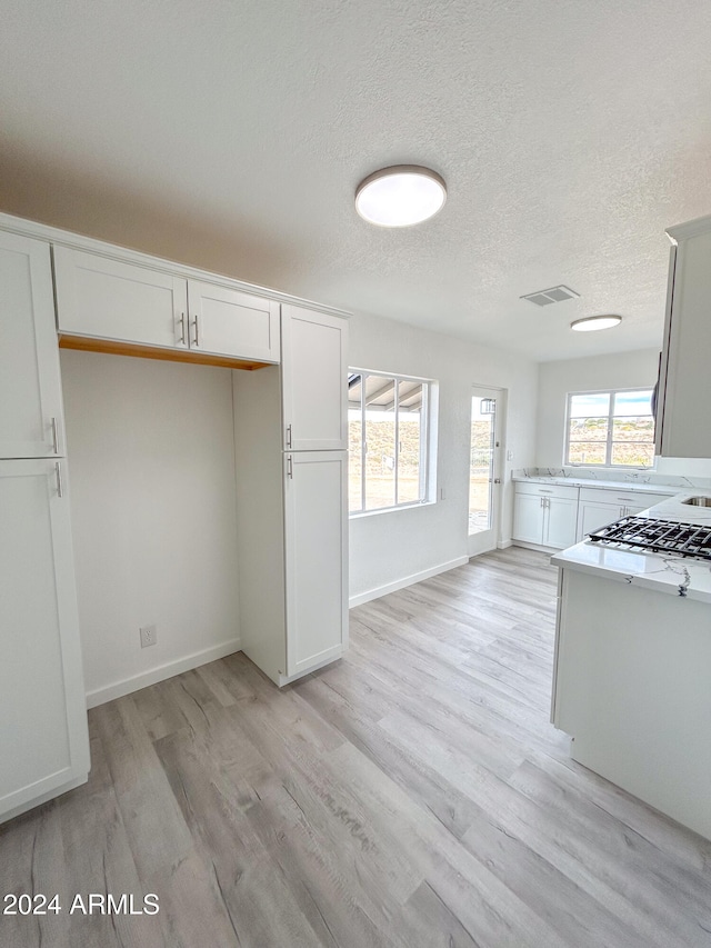 kitchen with white cabinets, light hardwood / wood-style floors, and a textured ceiling