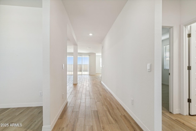 hallway featuring light wood finished floors and baseboards