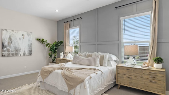 bedroom featuring light carpet, baseboards, and a decorative wall