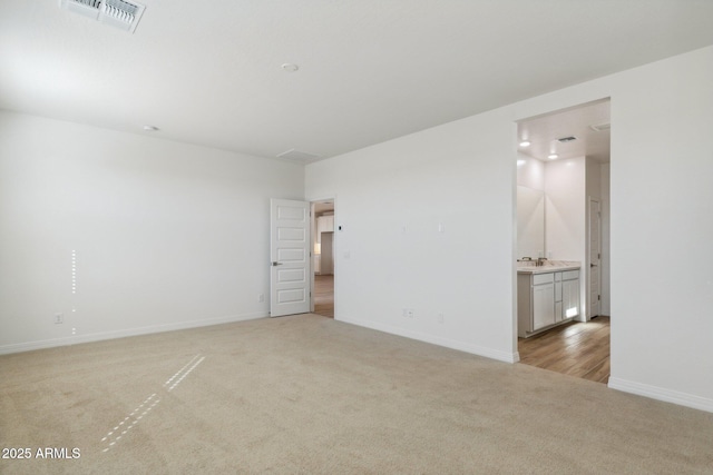 spare room featuring light carpet, baseboards, and visible vents