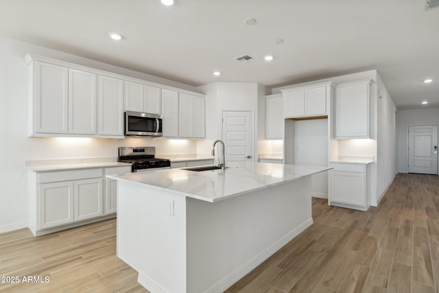 kitchen with light wood-style flooring, a sink, visible vents, white cabinetry, and appliances with stainless steel finishes