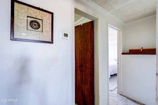 hallway featuring a textured ceiling and crown molding