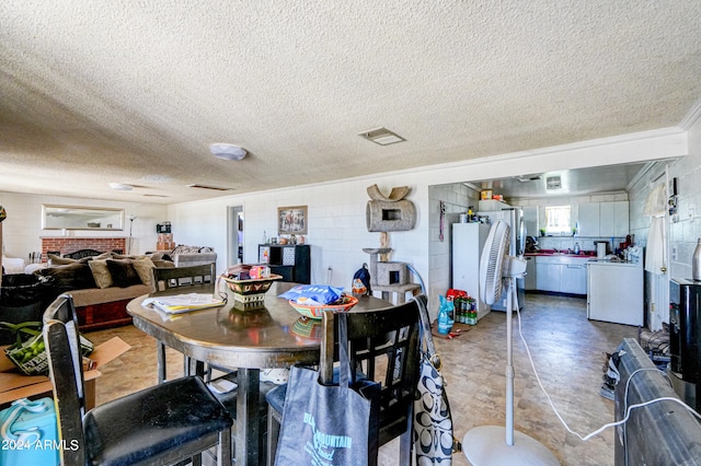 dining room featuring ornamental molding, a textured ceiling, and a brick fireplace