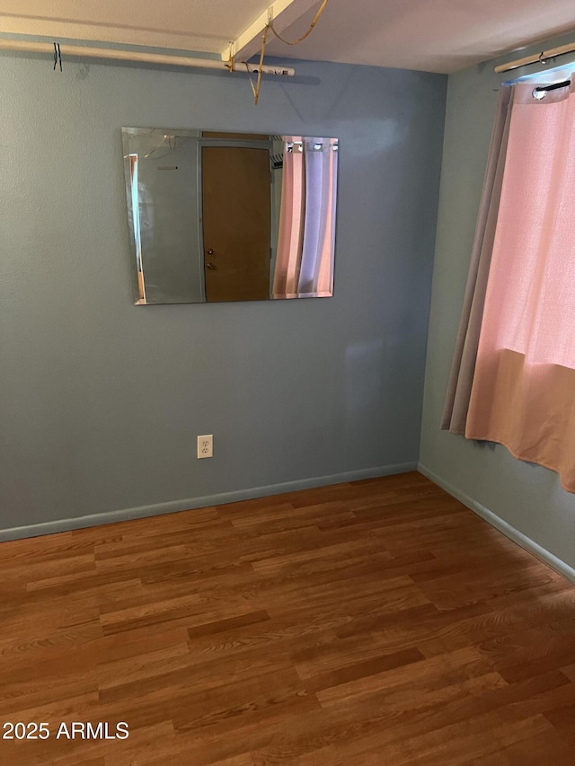 unfurnished room featuring baseboards and wood finished floors