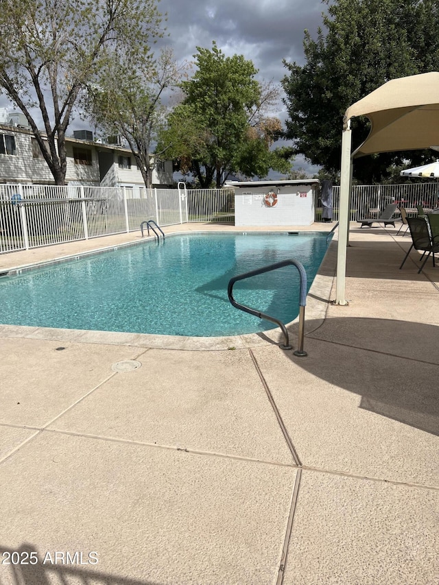 community pool with a patio area and fence