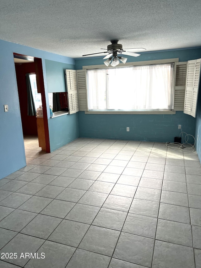 unfurnished room featuring a healthy amount of sunlight, light tile patterned floors, a textured ceiling, and a ceiling fan