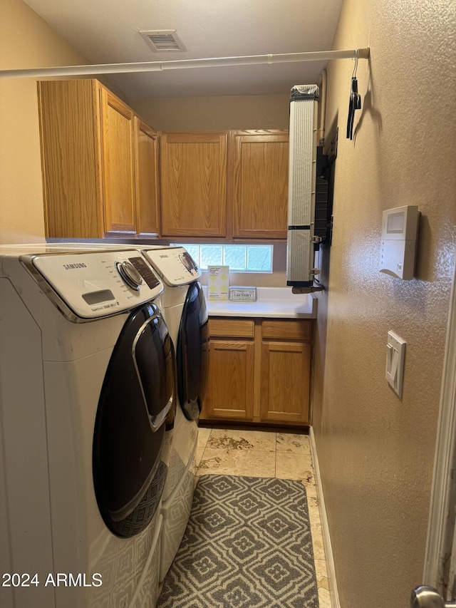 laundry area featuring cabinets, light tile patterned floors, and washer and dryer