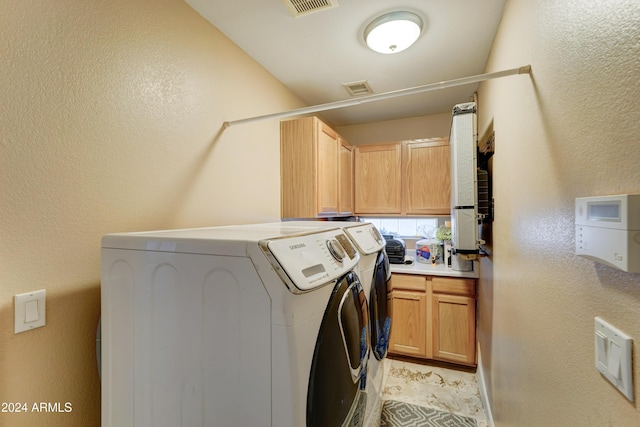 washroom featuring cabinets and washer and clothes dryer