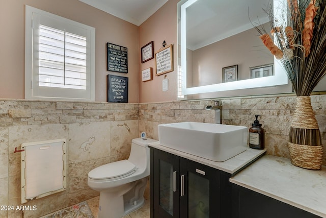 bathroom with vanity, toilet, and tile walls