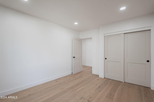 unfurnished bedroom featuring light wood-style flooring, baseboards, a closet, and recessed lighting