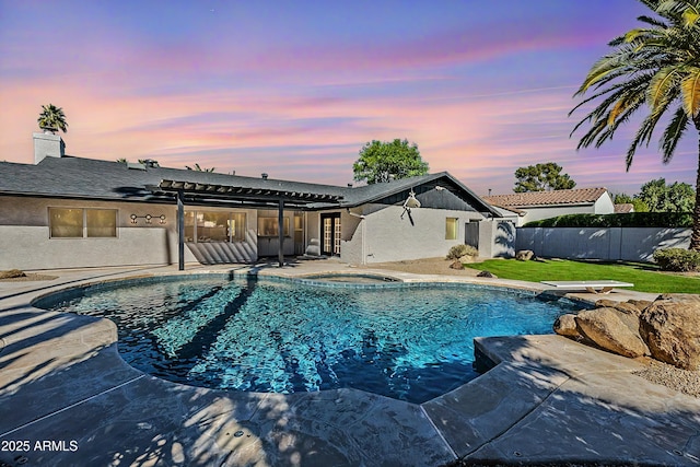 pool at dusk featuring a fenced in pool, a patio, an in ground hot tub, fence, and a diving board