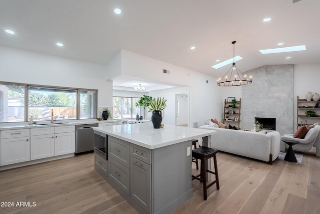 kitchen with light wood finished floors, a notable chandelier, dishwasher, and gray cabinetry