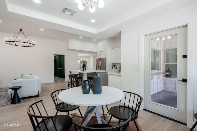 dining room featuring light wood-type flooring, visible vents, and a notable chandelier