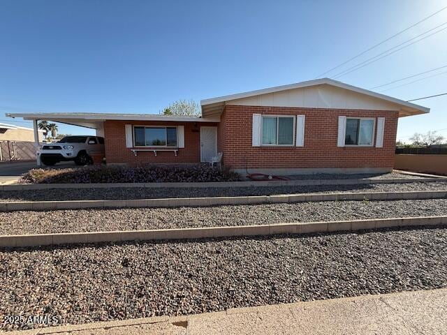 single story home featuring brick siding, an attached carport, and concrete driveway