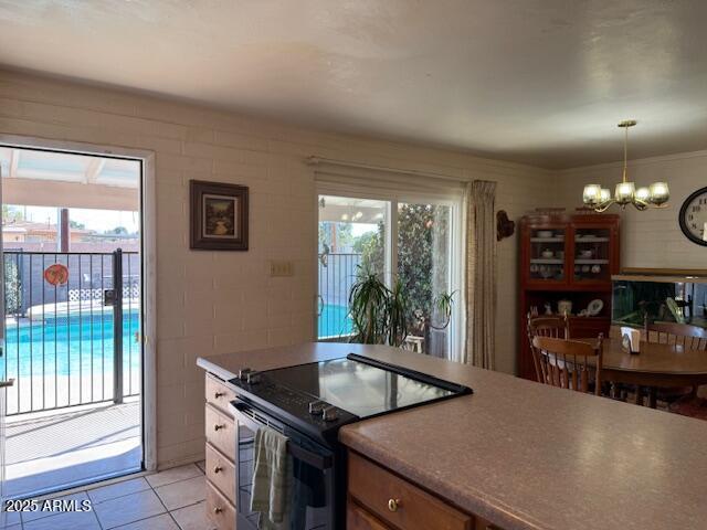 kitchen with a wealth of natural light, light tile patterned floors, a chandelier, and range with electric cooktop