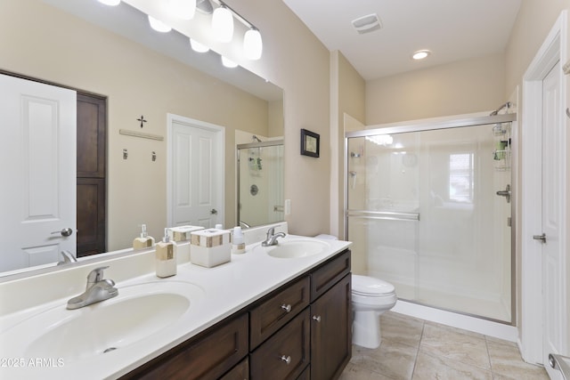 bathroom featuring a shower stall, double vanity, visible vents, and a sink