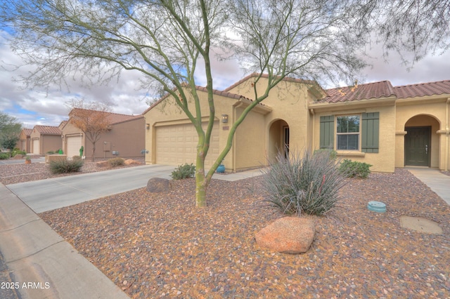 mediterranean / spanish home featuring a tiled roof, an attached garage, driveway, and stucco siding