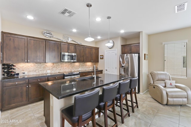 kitchen featuring visible vents, stainless steel appliances, decorative backsplash, and a sink