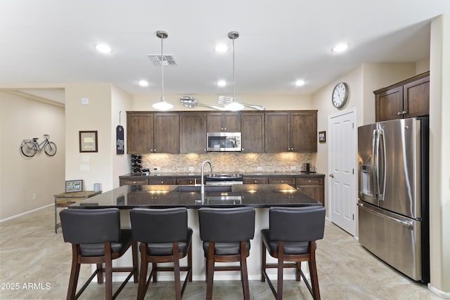 kitchen featuring visible vents, a sink, dark brown cabinetry, appliances with stainless steel finishes, and decorative backsplash