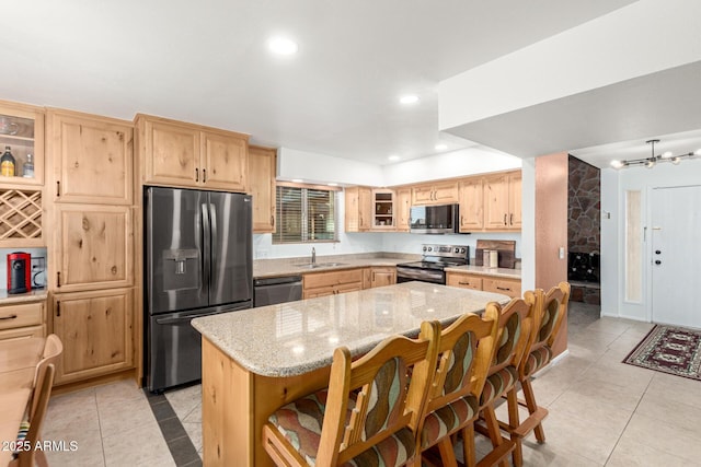 kitchen featuring light stone counters, stainless steel appliances, recessed lighting, light brown cabinetry, and glass insert cabinets