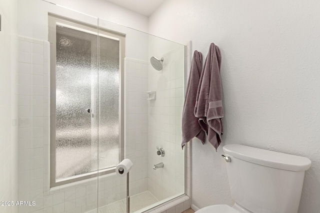 bathroom featuring a textured wall, a tile shower, and toilet