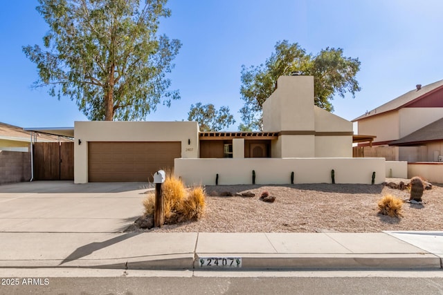 view of front of property featuring a garage, fence, concrete driveway, and stucco siding