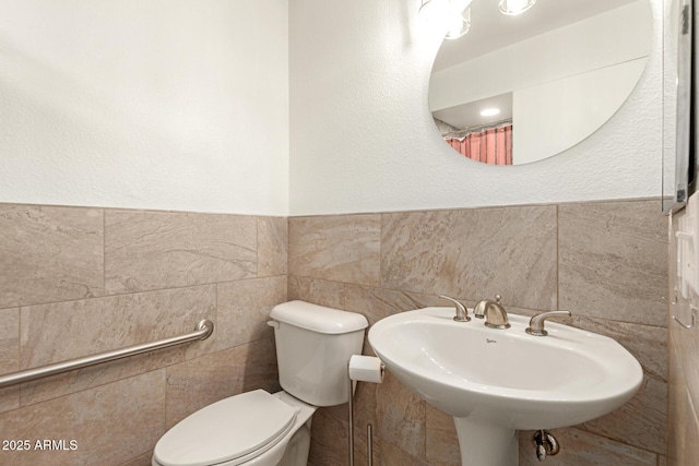 full bathroom featuring a sink, tile walls, and toilet