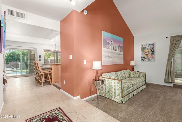 living room featuring carpet floors, lofted ceiling, visible vents, baseboards, and tile patterned floors