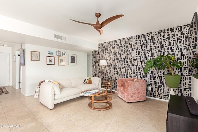 living room with light tile patterned floors, baseboards, visible vents, a ceiling fan, and an accent wall