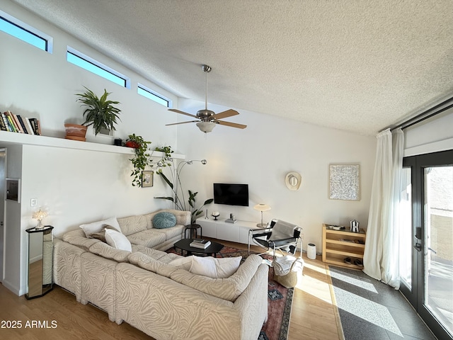 living room featuring lofted ceiling, a textured ceiling, hardwood / wood-style floors, and ceiling fan