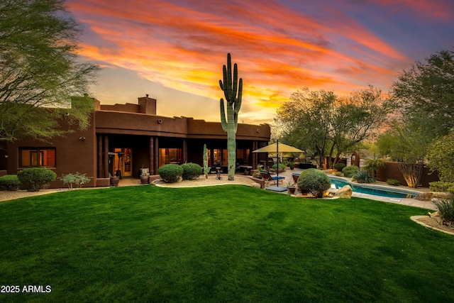 back house at dusk with a yard and a patio