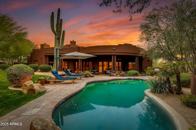 pool at dusk featuring a patio