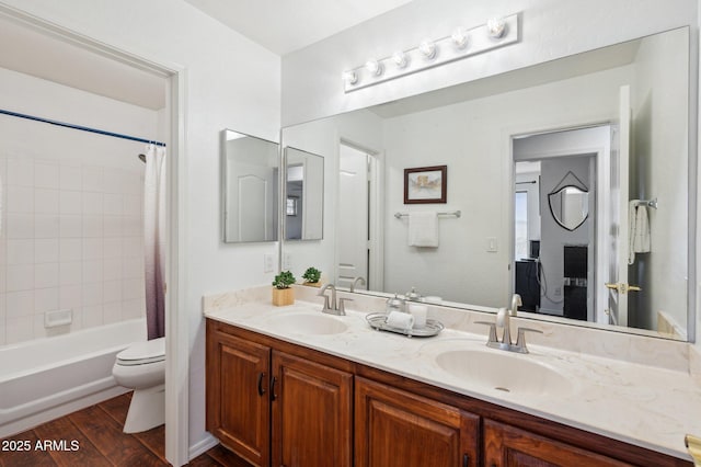 full bathroom featuring double vanity, wood finished floors, a sink, and toilet