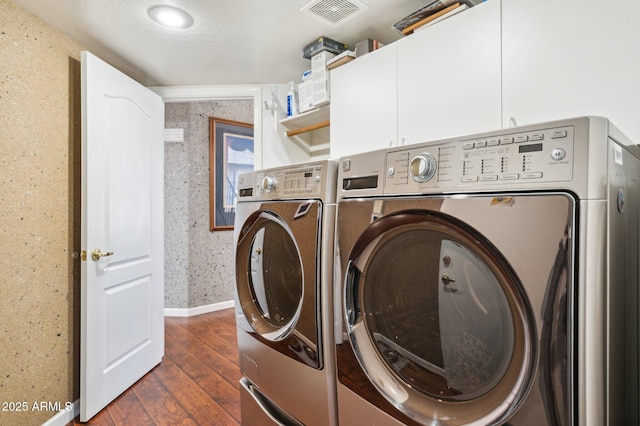 washroom featuring visible vents, cabinet space, washing machine and clothes dryer, and wallpapered walls