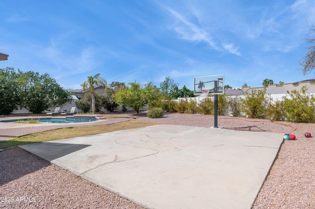 view of sport court featuring basketball hoop and an outdoor pool