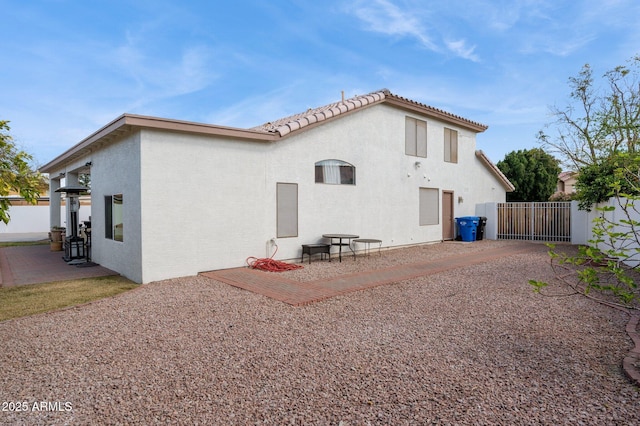 back of property with a patio, a tiled roof, a gate, fence, and stucco siding