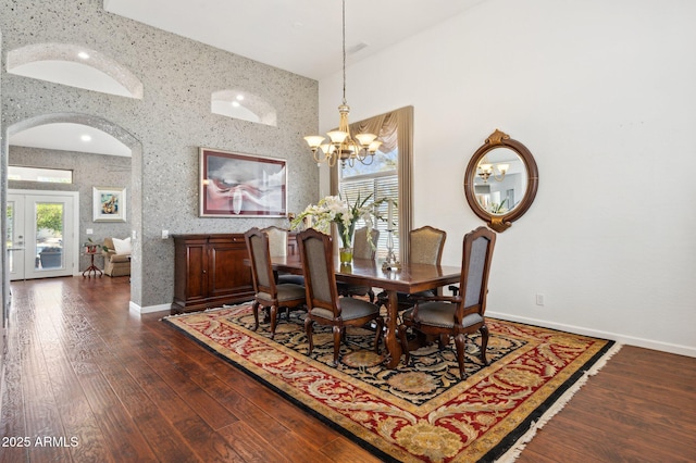 dining area with arched walkways, baseboards, hardwood / wood-style floors, and wallpapered walls