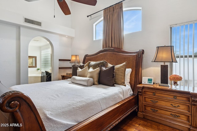 bedroom featuring visible vents, arched walkways, ceiling fan, dark wood-type flooring, and ensuite bathroom