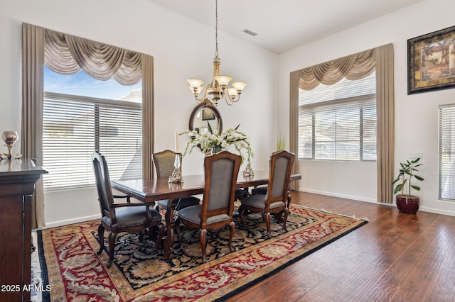 dining space with lofted ceiling, an inviting chandelier, a wealth of natural light, and wood finished floors