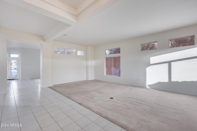 empty room featuring beamed ceiling and light colored carpet