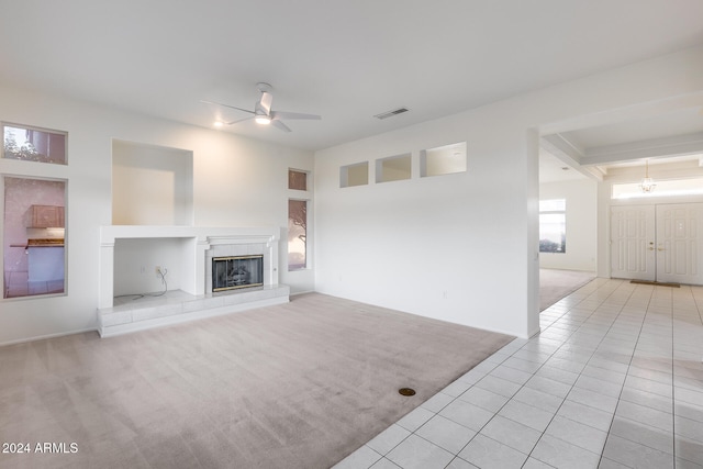 unfurnished living room featuring ceiling fan, light tile patterned floors, and a tile fireplace