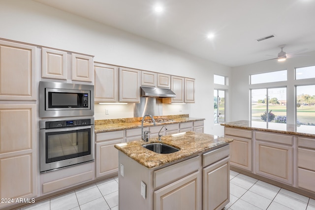 kitchen featuring light stone countertops, sink, stainless steel appliances, a kitchen island with sink, and light tile patterned floors