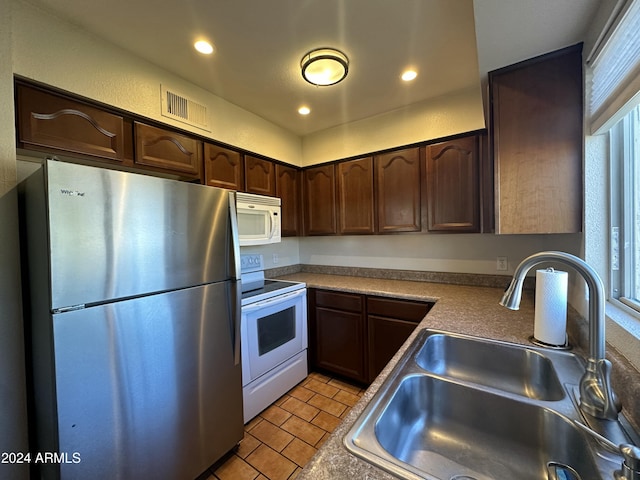 kitchen featuring dark brown cabinetry, white appliances, sink, and a wealth of natural light