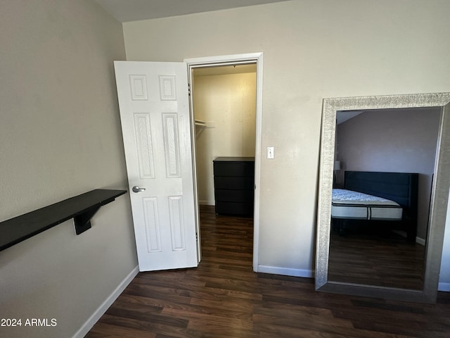 unfurnished bedroom with dark hardwood / wood-style flooring, a spacious closet, and a closet