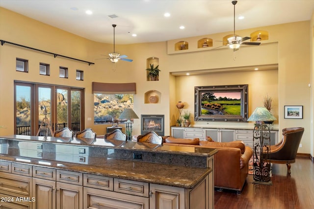 kitchen featuring dark stone counters, french doors, ceiling fan, dark hardwood / wood-style floors, and a kitchen island