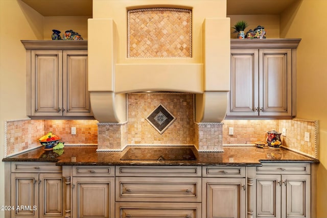 kitchen with black electric stovetop, backsplash, and dark stone counters