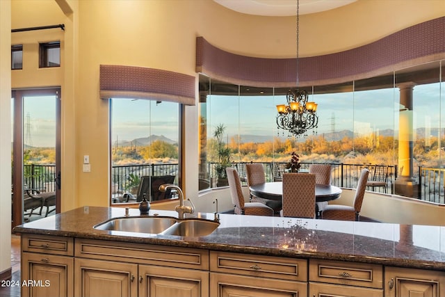 kitchen featuring dark stone counters, sink, pendant lighting, a mountain view, and a chandelier